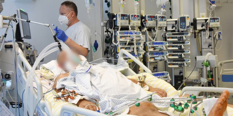 Auf einer Intensivtherapie-Station versorgt einen Oberarzt einen schwer an Corona erkrankten Patienten.