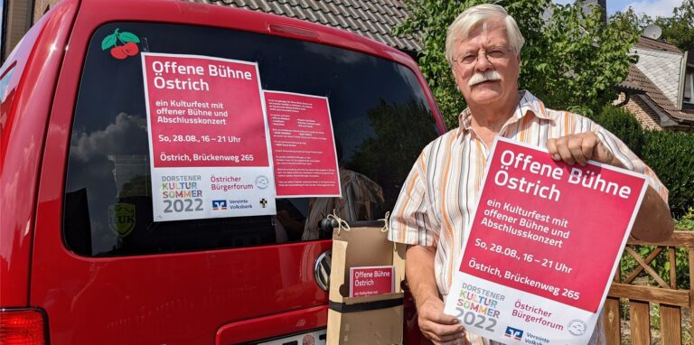 Werner Kapteinat zeigt ein Plakat in die Kamera.