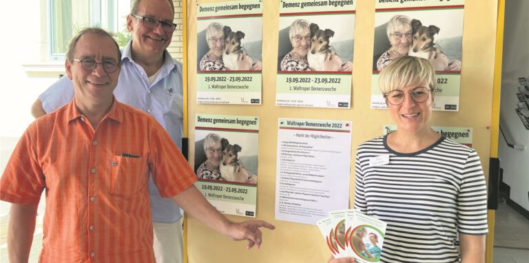 VHS-Vize Andreas Guderian, Pflegewissenschaftler Jörg Burbaum und Altenhilfekoordinatorin Alexandra Wittor weisen auf Plakate zur Waltroper Demenzwoche hin.