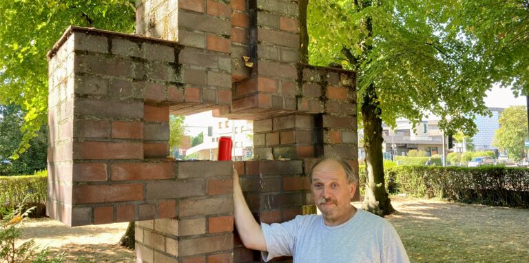 Küster Andreas Pieper mit einer Grabkerze vor dem leeren Kreuz.