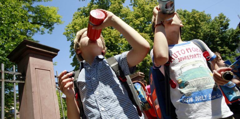 Die beiden neunjährigen Jungen Jakob (l) und Anton (r) gönnen sich vor einer Grundschule einen Schluck aus der Wasserflasche.