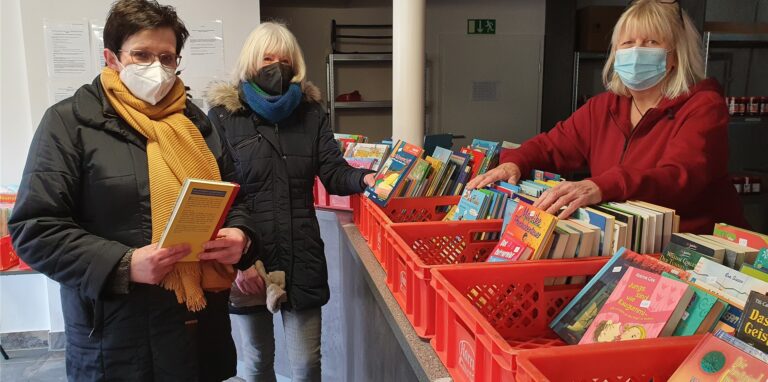 Drei Frauen stehen vor Kisten mit Büchern
