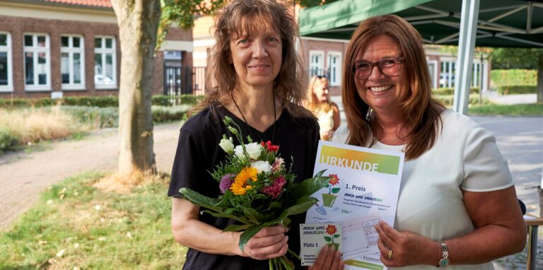 Elke Lange (links) aus Herten-Disteln ist diesjährige Gewinnerin des Vorgartenwettbewerbs. Die stellvertretende Bürgermeisterin Silvia Godde, überreicht den Preis.