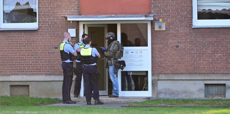 Auf diesem Bild aus dem Jahr 2020 stehen Polizei und ein SEK-Beamter vor der Eingangstür eines Mehrfamilienhauses (Symbolbild).