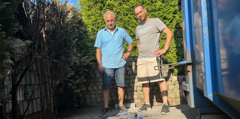 Bayram Küplüce und Tobias Krone stehen neben der Stelle, wo eine blaue Mülltonne abbrannte und die Hecke Feuer fing.