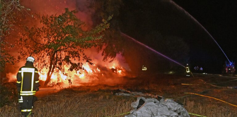 Ein Strohlager brennt in Lembeck. Feuerwehrleute löschen das Feuer.