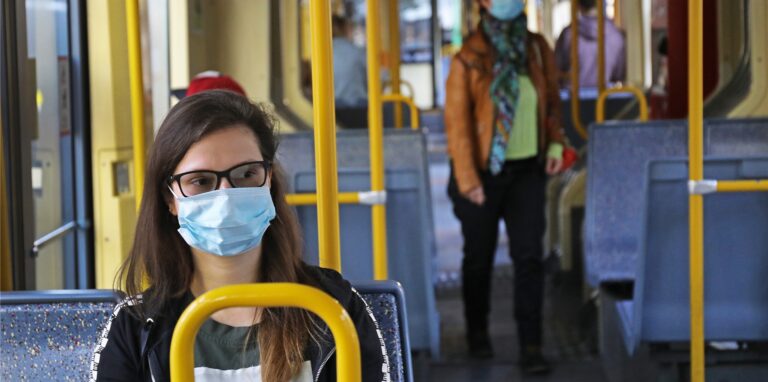 Reisende mit Maske in einer Bahn.