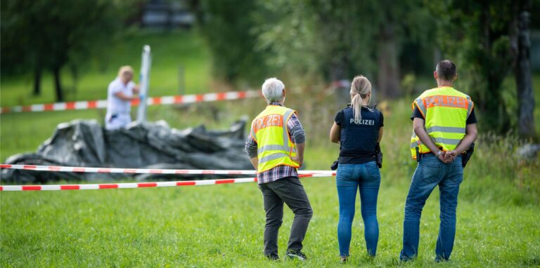Polizisten stehen an einem abgesperrten Bereich an einem Bachlauf