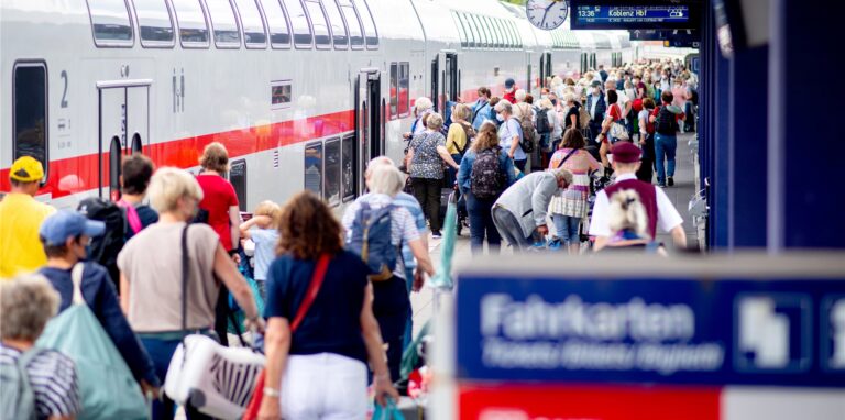 Fahrgäste gehen über einen Bahnsteig zu einem IC.