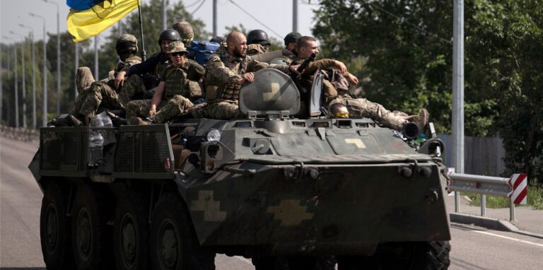 Ukrainische Soldaten fahren auf einem gepanzerten Fahrzeug auf einer Straße.