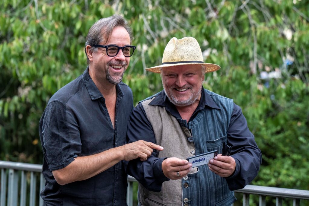 Die «Tatort»-Schauspieler Jan Josef Liefers (l) und Axel Prahl schauen auf ein Smartphone und lachen.