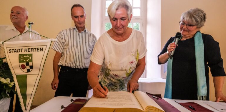 Heike Koser trägt sich in das Goldene Buch der Stadt Herten ein. Mit ihrem Mann Klaus Koser (2.v.l.) wird sie für ihr langjähriges Engagement für Pflegekinder mit Handicap ausgezeichnet.