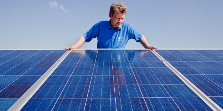 Ein Techniker überprüft Photovoltaik-Module auf dem Dach eines Hauses.