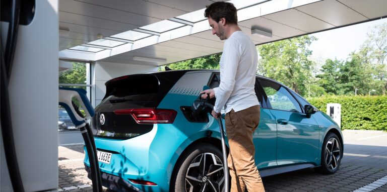 Ein Mann lädt sein E-Auto an einer Ladestation auf.