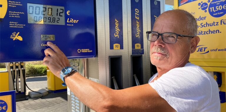 Ein Mann steht an einer Zapfsäule an einer Tankstelle in Recklinghausen und zeigt mit der linken Hand auf die Anzeige für den Benzinpreis. 204,9 steht dort.
