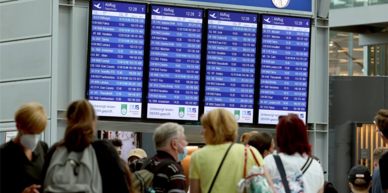 Reisende stehen im Flughafen Düsseldorf vor der Tafel mit den Abflugdaten.