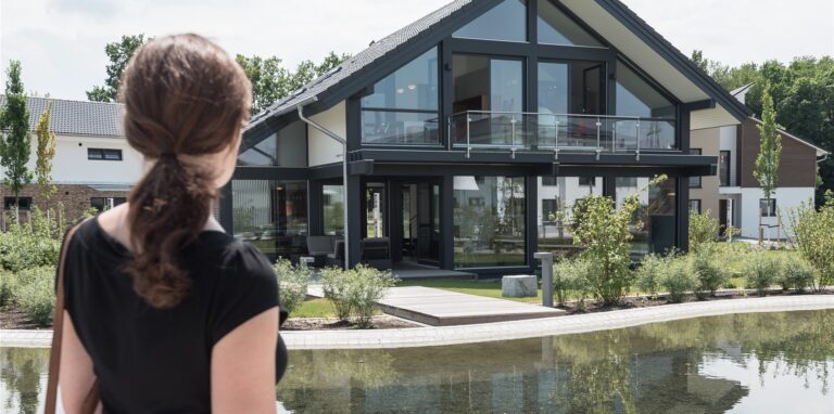 Eine Frau steht vor einem Haus und betrachtet es.