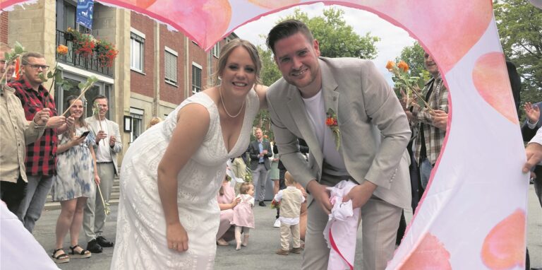 Das Hochzeitspaar Jennifer Caspers und Florian Witte schaut durch das freigeschnittene Herz.