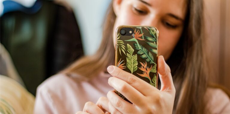 Eine junge Frau hält ein Handy in der Hand.