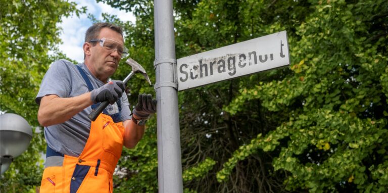 Ein Mann entfernt ein altes Straßenschild.