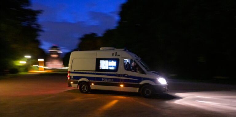 Ein Polizeifahrzeug fährt durch eine dunkele Straße.