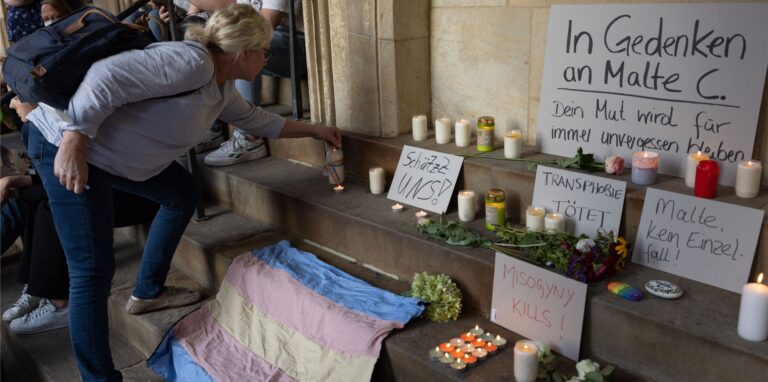 Eine Frau entzündet eine Kerze in Gedenken an Malte C.. Menschen demonstrieren auf dem Prinzipalmarkt gegen Gewalt an queeren Menschen.