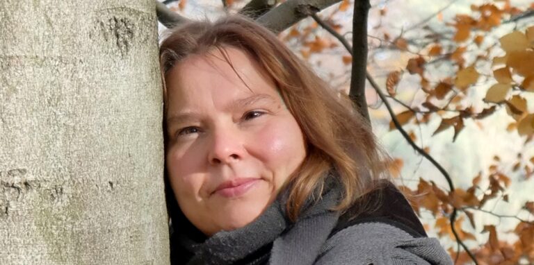 Künstler Cornelia Cintosun  lehnt sich an einen Baum.