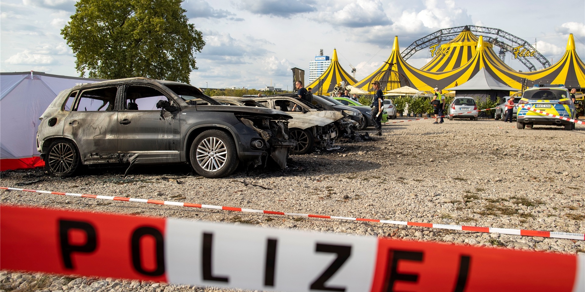 Ausgebrannte Fahrzeuge stehen vor dem Zelt des Zirkus FlicFlac, nachdem dort ein Kleinflugzeug abgestürzt war.