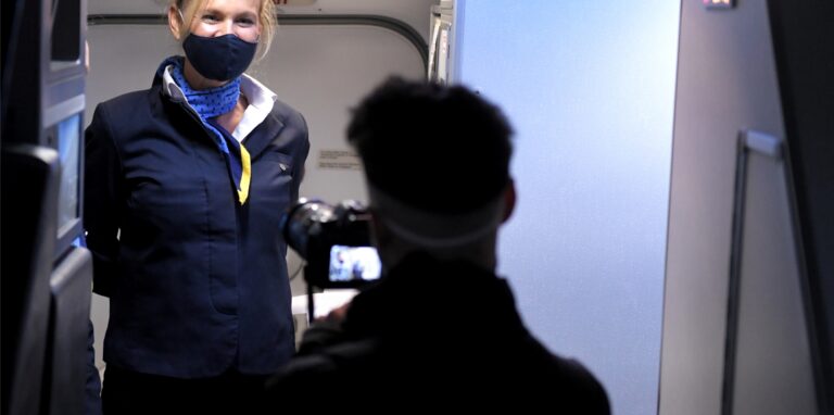 Eine Flugbegleiterin empfängt einen Reisenden an Bord einer Maschine.