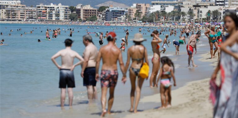 Menschen genießen die Sonne am Strand von Arenal nahe Palma auf Mallorca.