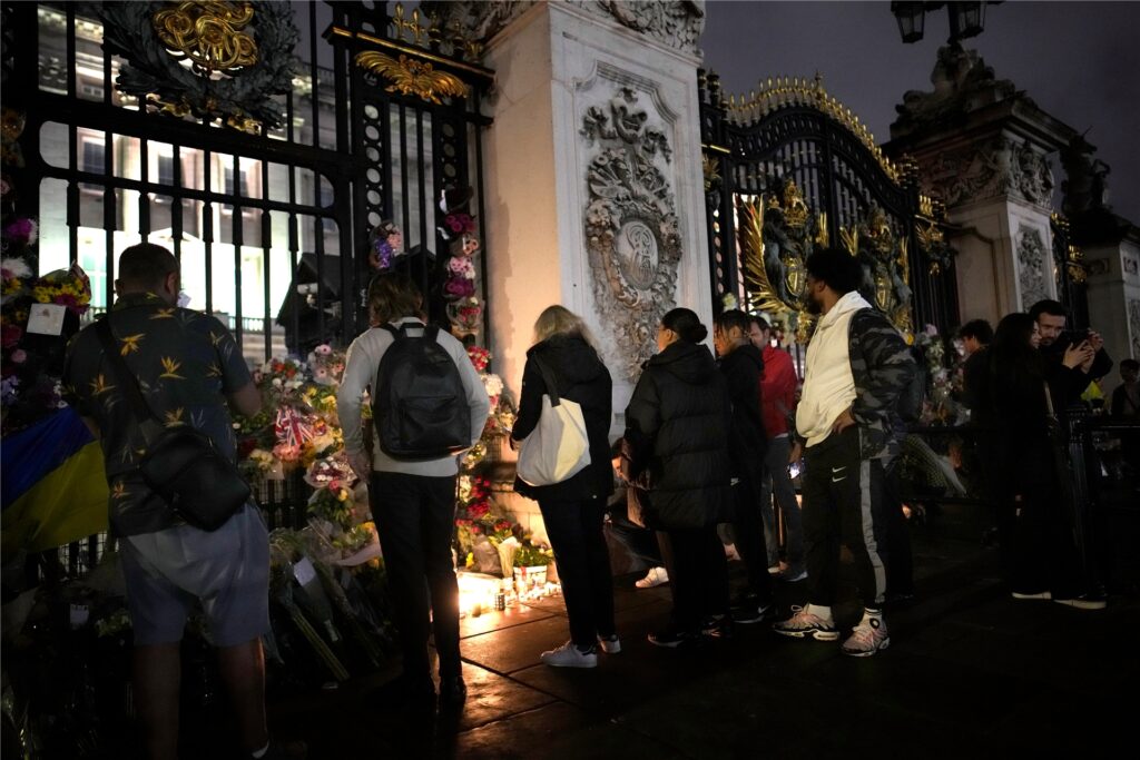 Menschen stehen vor den Toren des Buckingham Palace in London. Blumen und Kerzen wurden niedergelegt. Menschen stehen vor den Toren des Buckingham Palace in London. Blumen und Kerzen wurden niedergelegt.