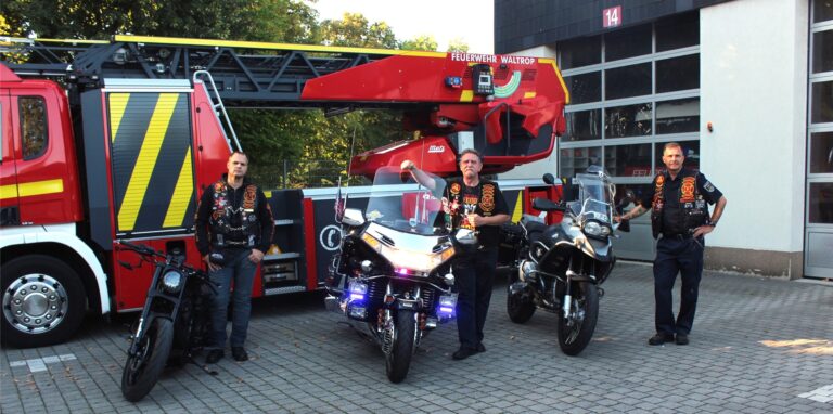 Drei Männer mit Motorrädern stehen vor einem Feuerwehrfahrzeug in Waltrop.