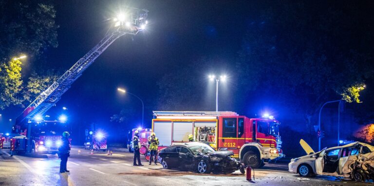 Feuerwehrwagen und Einsatzkräfte stehen neben den zwei Autos, die am Samstagnacht verunglückt sind.