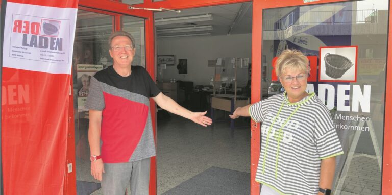 Peter Hirsch vom Laden und Christiane Jurgeleit-Höflich von der Caritas weisen auf die offene Tür den Ladens hin.
