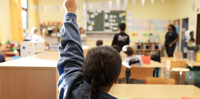 Eine Schülerin zeigt in der Grundschule im Unterricht auf.