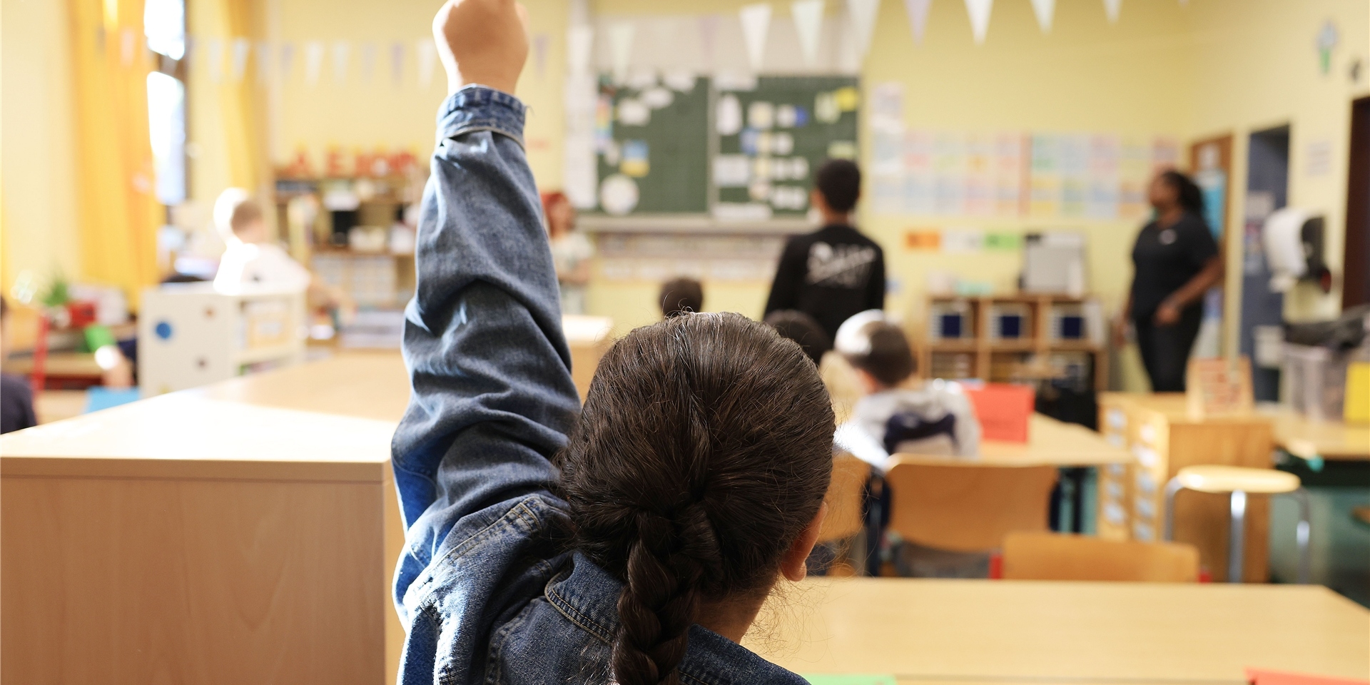 Eine Schülerin zeigt in der Grundschule im Unterricht auf.