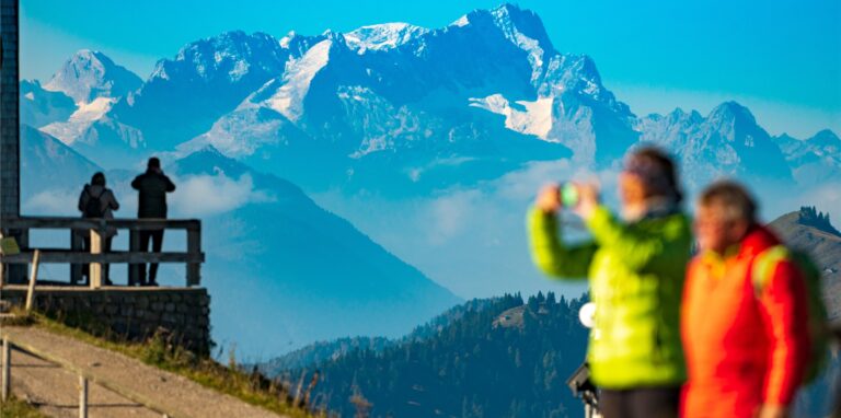 Besucher stehen in den Morgenstunden auf dem Wallberg vor der imposanten Kulisse der Zugspitze, die im Hintergrund in den Himmel ragt.