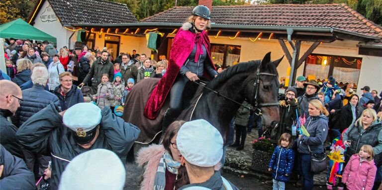 Eine Frau reitet als St. Martin verkleidet durch die Kleingartenanlage.