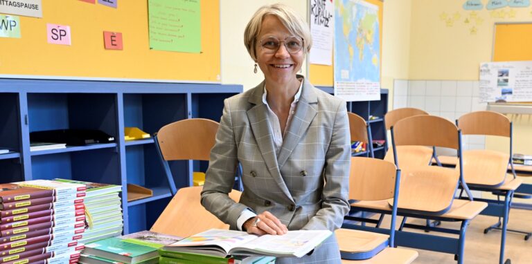 NRW-Schulministerin Dorothee Feller vor Stapeln mit Schulbüchern