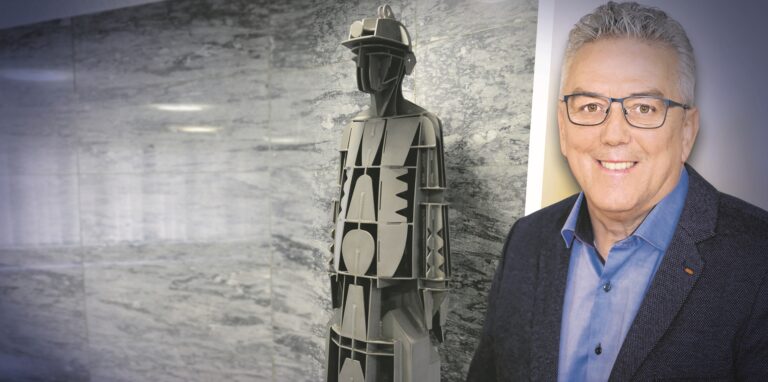 Ein Mann steht neben einer Stahlfigur