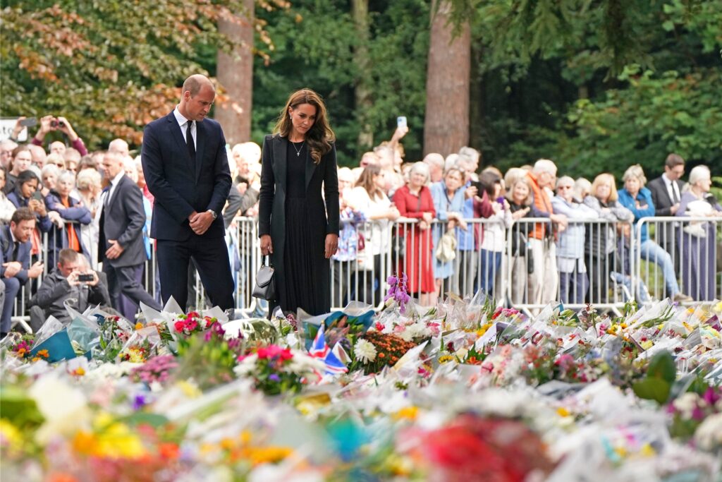 Prinz William (r), Prinz von Wales, und Kate, Prinzessin von Wales, betrachten die Blumen, die nach dem Tod von Königin Elizabeth II. von der Öffentlichkeit vor den Toren von Sandringham House niedergelegt wurden.