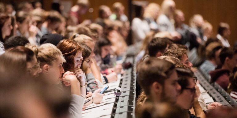 Studenten verfolgen im Hörsaal im Hauptgebäude der Universität die Erstsemesterbegrüßung.