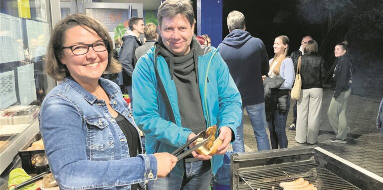 THG-Direktorin Sonja Leukefeld legt ein gebratenes Schnitzel in ein Brötchen, das der Fördervereins-Vorsitzende Michael Braun in den Händen hält.