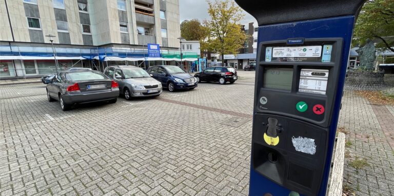 Ein Parkscheinautomat steht auf dem Marktplatz in Herten-Mitte vor mehreren parkenden Autos.
