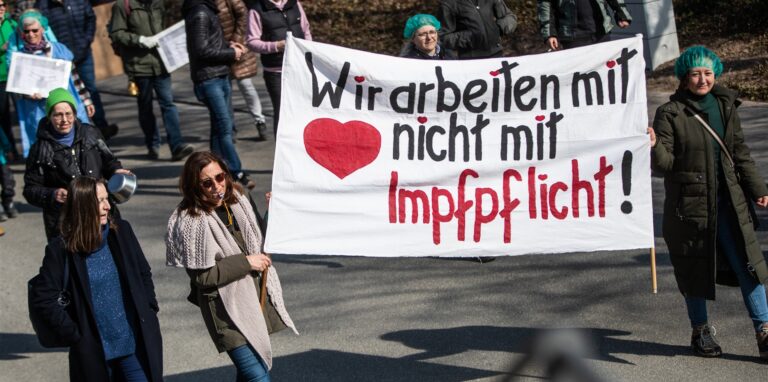„Wir arbeiten mit Herz, nicht mit Impfpflicht!“ steht auf einem Plakat, das Menschen bei einer Demonstration gegen die Corona-Maßnahmen der Bundesregierung zeigen.
