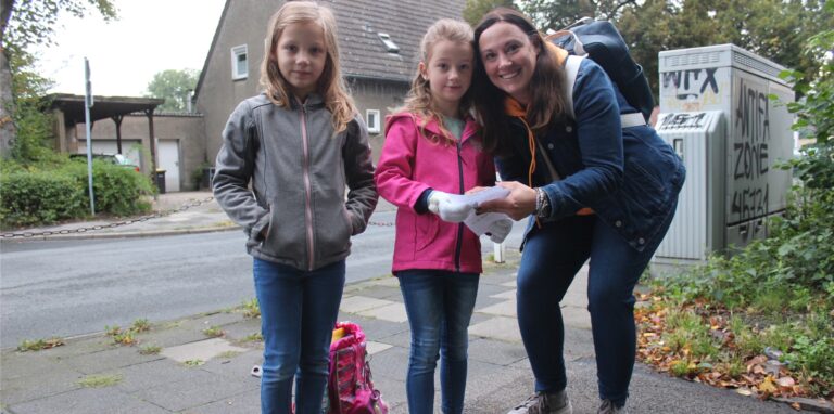 Zwei Mädchen stehen mit einer Erwachsenen Frau an einer Straße in Waltrop.
