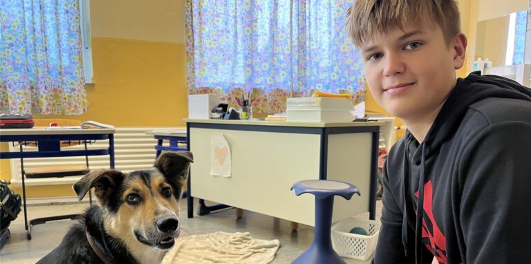 Daniel aus Klasse 7 der Achtenbeckschule in Herten-Disteln kniet neben Schulhund Monty.