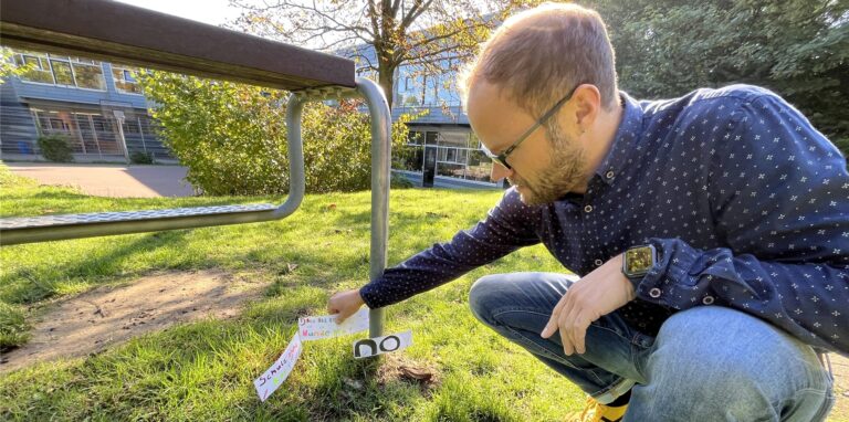 Schulleiter Tobias Gahlen steckt an der Achtenbeckschule in Herten drei Hinweiszettel in den Boden.