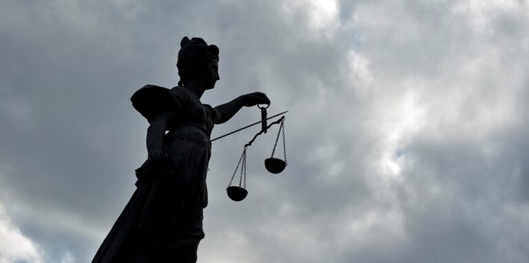 Eine Statue der Justitia hält eine Waagschale