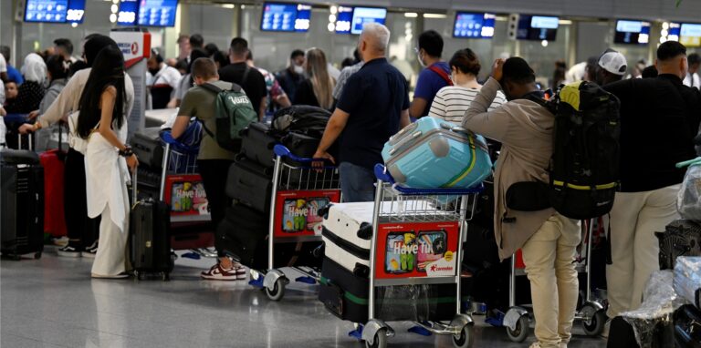 Reisende stehen in Schlangen vor den Check-In-Schaltern im Terminal am Düsseldorfer Flughafen.